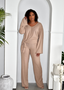 Woman wearing beige ribbed knit lounge set with tie waist, standing in minimalist archway