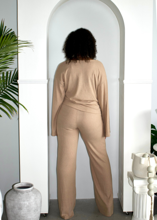 Woman wearing beige ribbed lounge set in a resort-inspired, minimalist archway setting