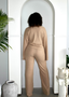 Woman wearing beige ribbed lounge set in a resort-inspired, minimalist archway setting