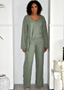 Woman wearing sage green ribbed lounge set with long sleeves and tie waist in modern interior