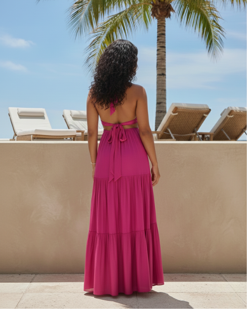 Woman in magenta resort dress by poolside with palm tree and lounge chairs on sunny day