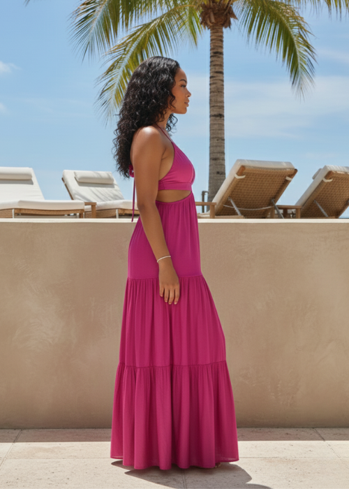 Woman in a pink tiered maxi dress by poolside with palm tree and lounge chairs, resortwear style