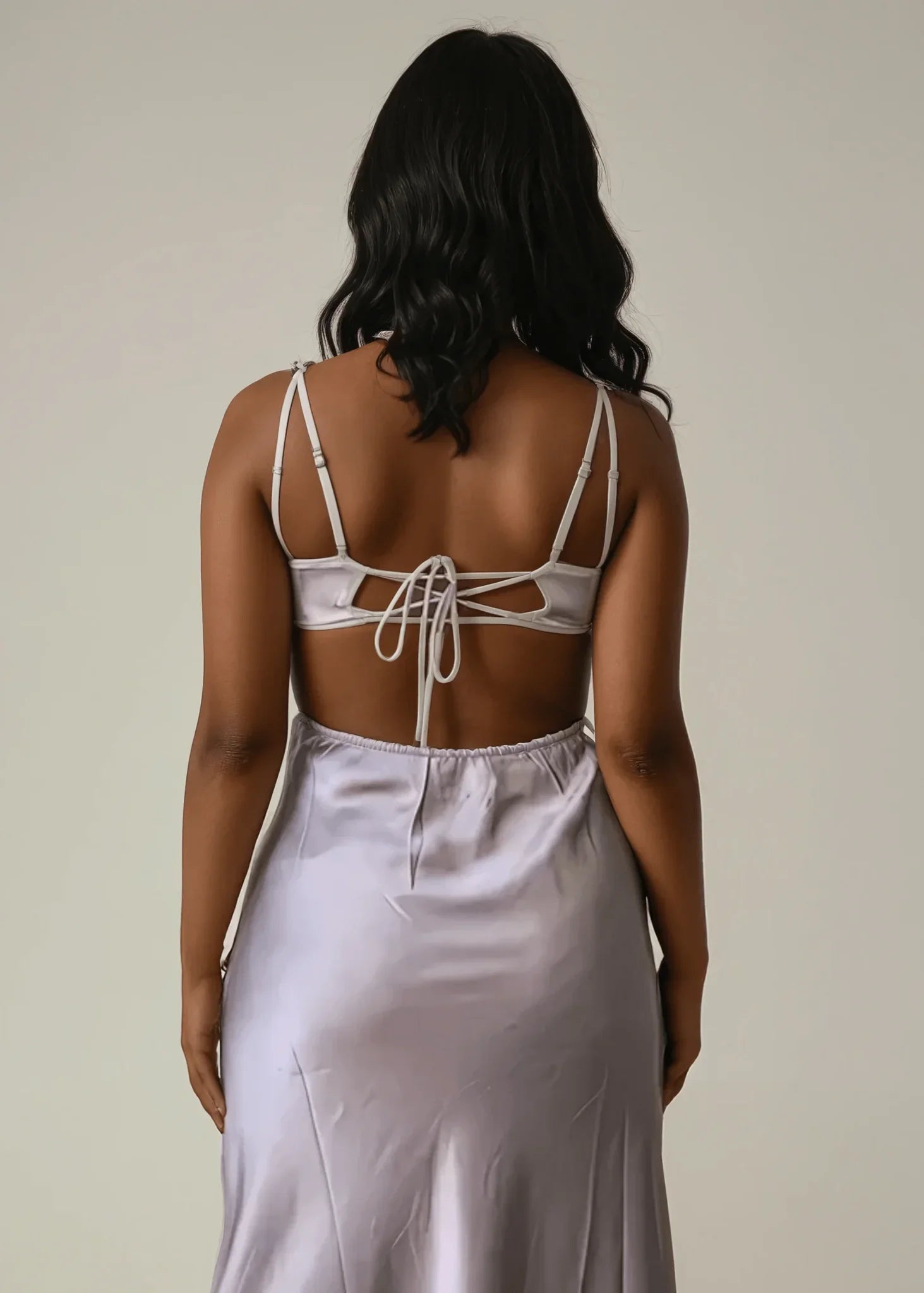 Back view of woman in mocha satin cut-out maxi dress with tie detail and adjustable straps