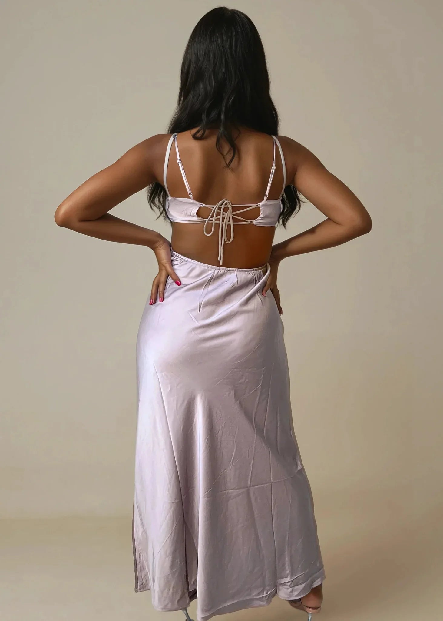 Back view of woman in mocha satin cut-out maxi dress with tie-back details